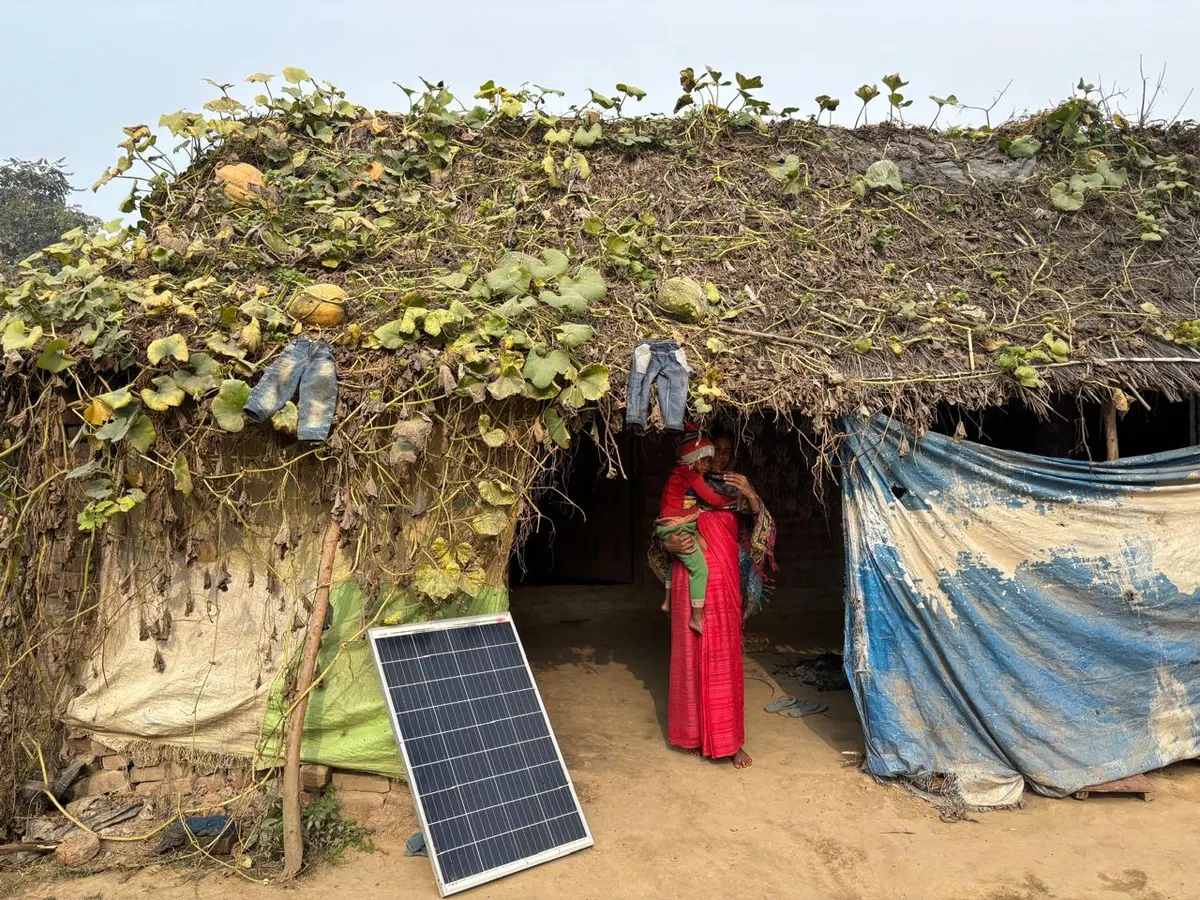 A solar panel set up outside a thatched rural home